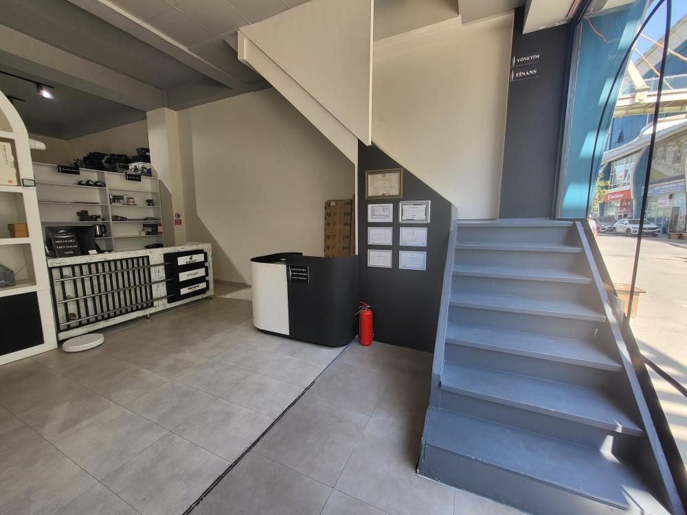 The reception counter, framed documents on the wall behind it and grey stairs up to the offices on the upper floor