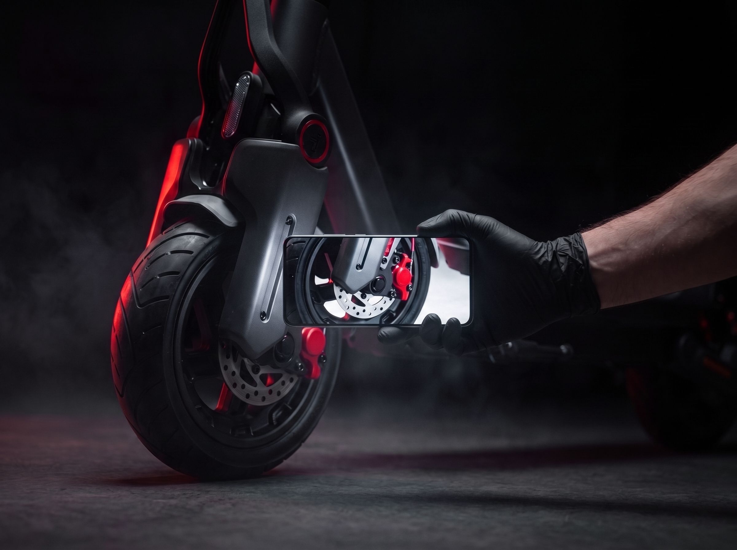 A gloved hand photographing a scooter's rear brake caliper with a phone